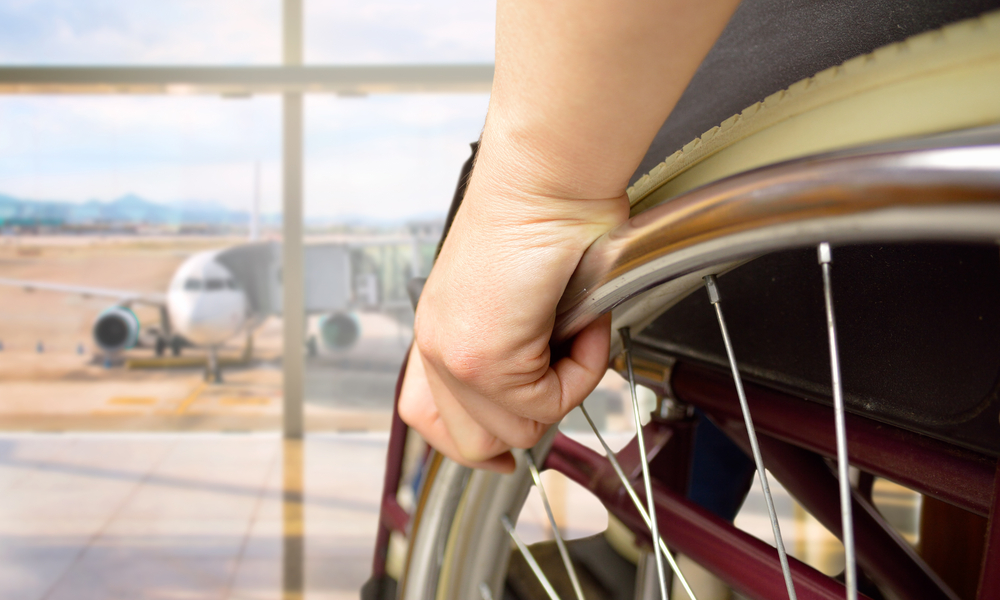 rear view of a man in wheelchair at the airport with focus on hand