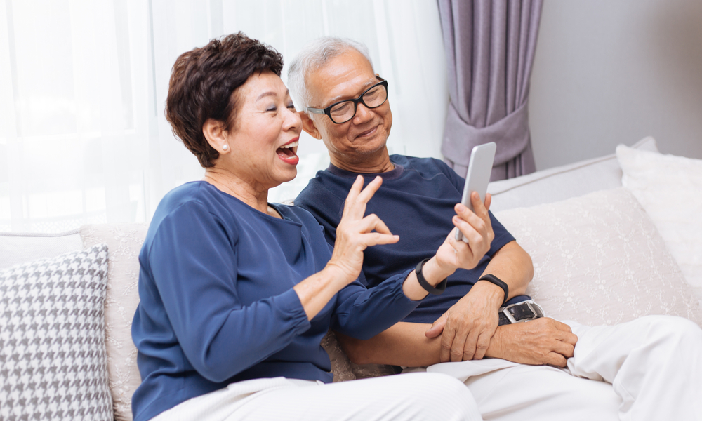 Senior Asian couple grandparents making a video call and waving at the caller
