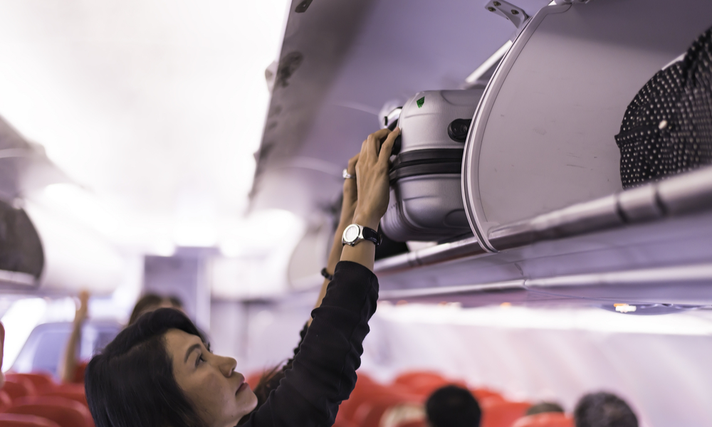 Traveller woman open overhead locker on airplane