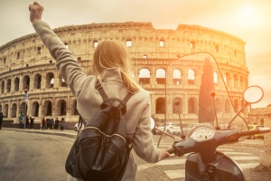 Woman tourist near the Coliseum in Rome under sunlight and blue sky.