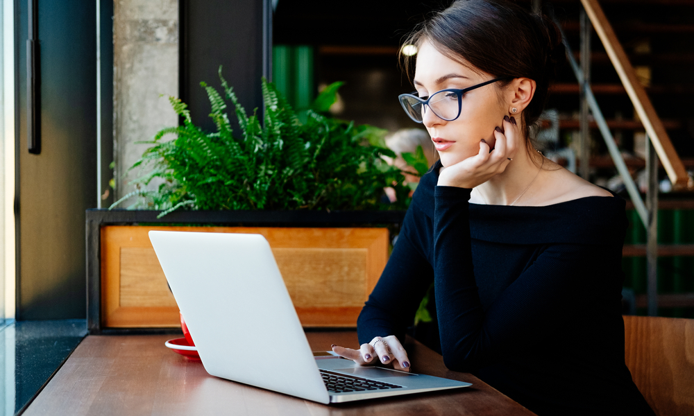 How to stay safe abroad: woman in glasses sitting on cafe and using laptop