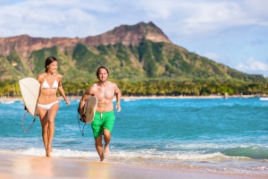 The Best Places to Surf in Hawaii in the Winter Season: Happy surf people having fun surfing on Waikiki beach, Honolulu, Oahu, Hawaii.