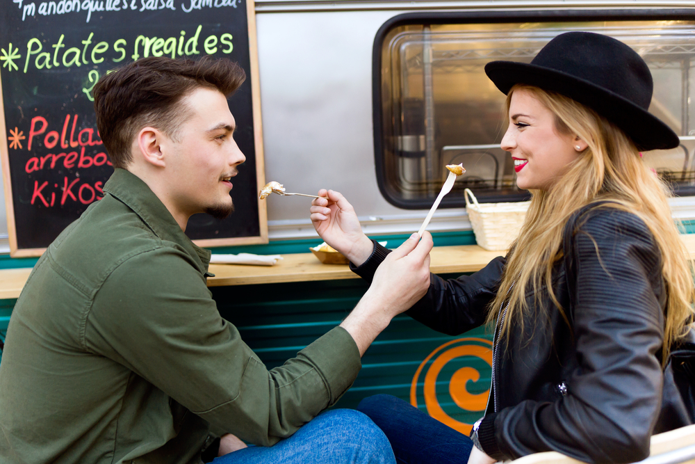 man and woman sharing food at a food truck 