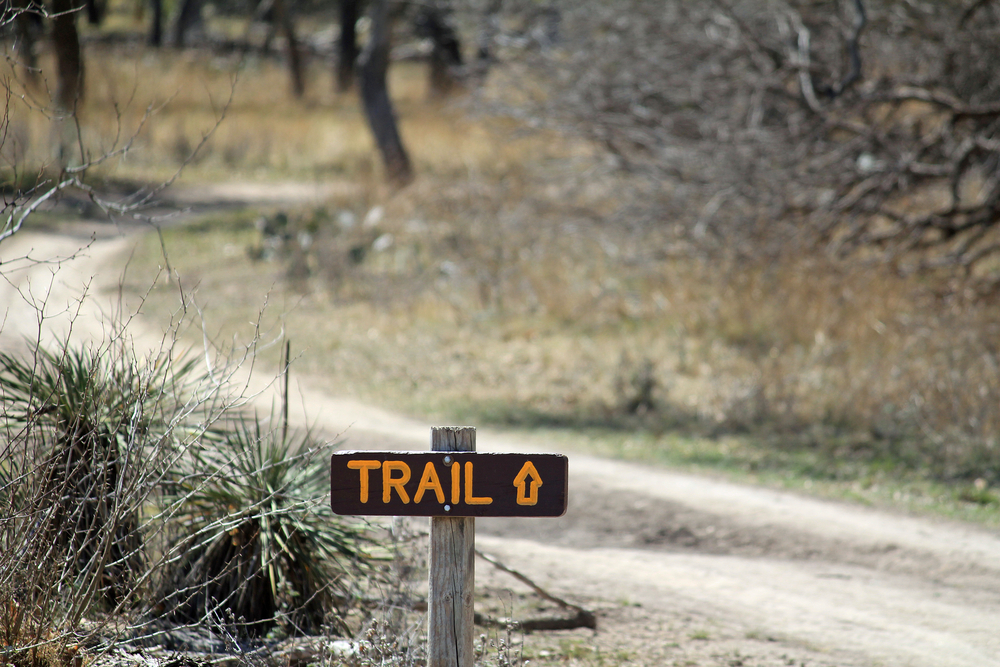 Trail sign pointing the way along hike and bike trail through the Pecan Bottom area of South Llano River State Park near Junction, Texas.