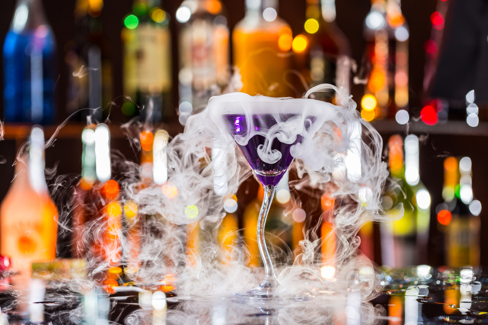 Martini drink served on bar counter with blur bottles on background