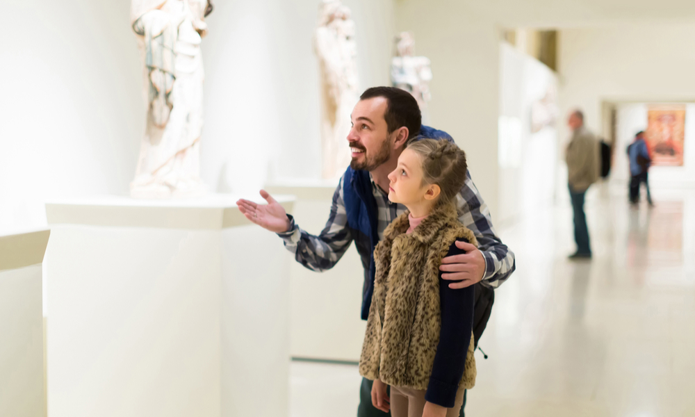 happy father and daughter looking at ancient bas-reliefs in museum