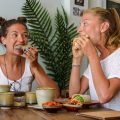 Young women eating vegetarian food and drink coffee in a cafe