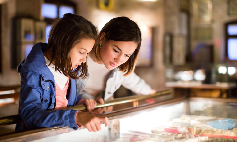 Happy mother and daughter exploring expositions of previous centuries in museum